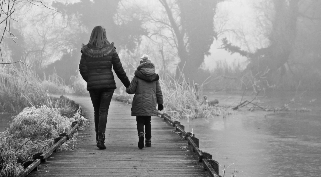 Mère et fille se tenant la main et marchant sur un pont au dessus d'un lac
