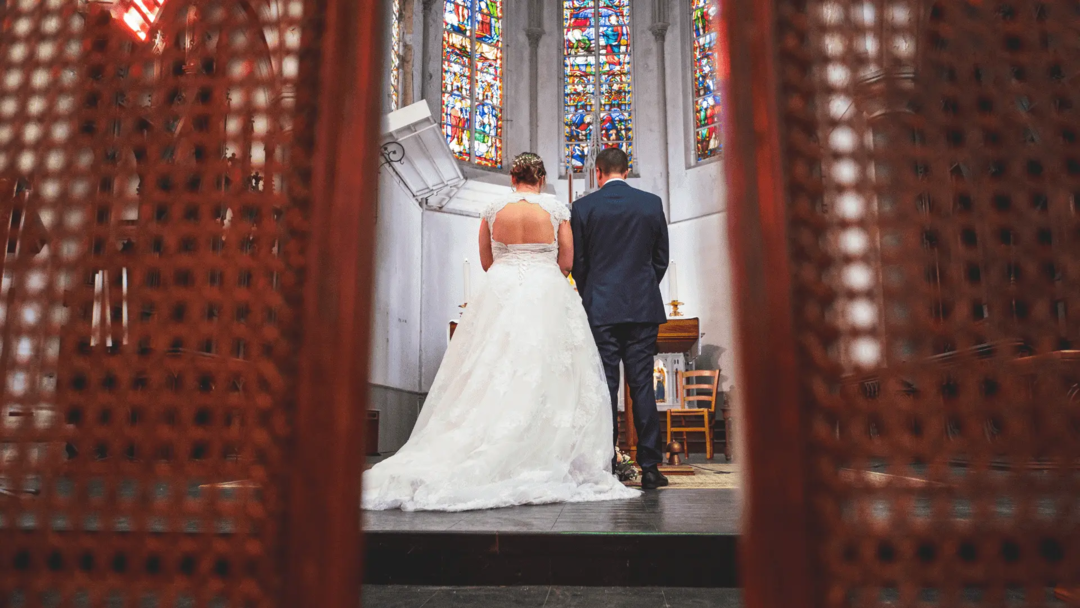 Mariés de dos se tenant devant l'autel dans une église