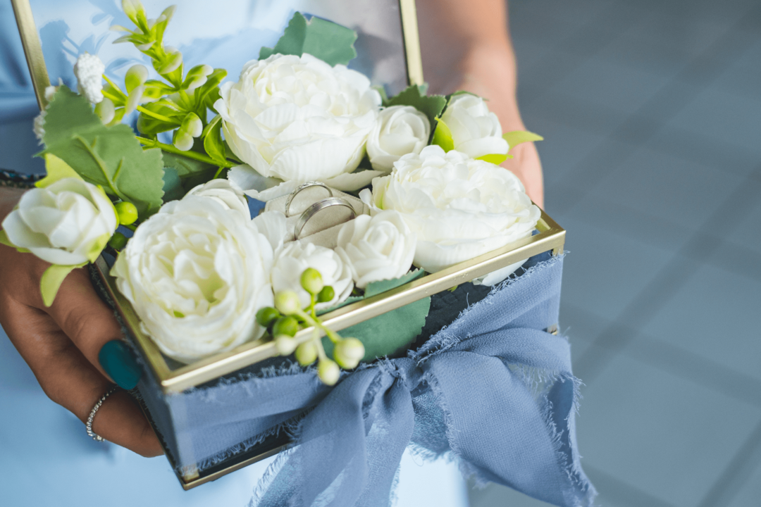 Présentation d'un coffret avec deux alliances posées sur un bouquet de fleurs blanches