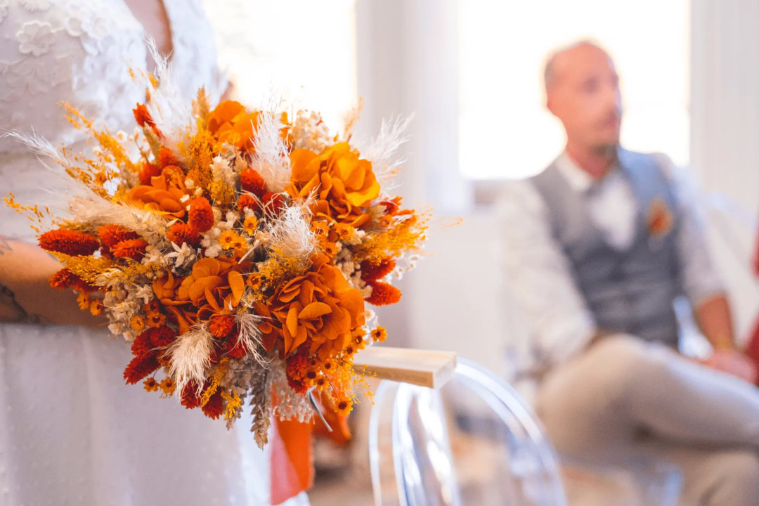 Focus sur le bouquet de la mariée composé de fleurs oranges